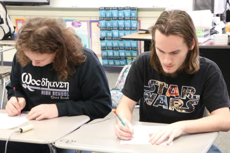 Teagan Fynan and Damien Foster race to solve problems during the math category of the Students v. Staff Quiz Bowl Meet.