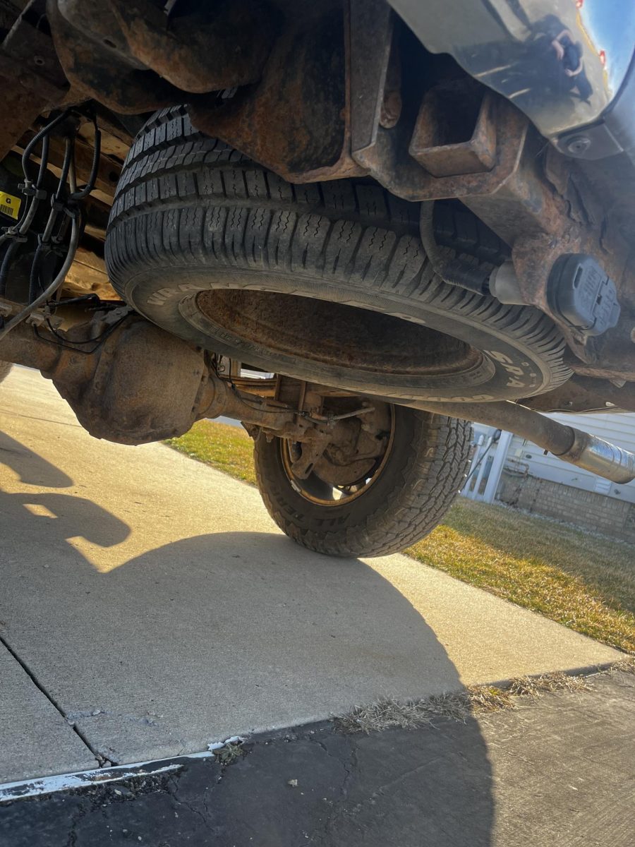 Remove the spare tire from either the trunk of the car, commonly under the trunk floor, or if an SUV or truck, it will be under the vehicle in the rear. 