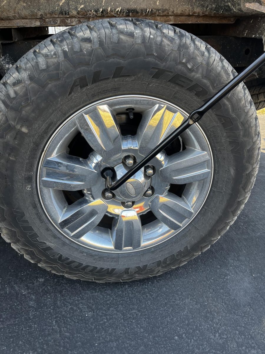 While the car is still on the ground, grab the tire iron and loosen the lug nuts on the tire.